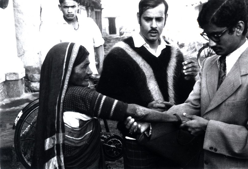 Dr Gopal Dass examines a patient on a village survey. Mr Patole, paramedical supervisor, to left of Dr Dass. Belgaum