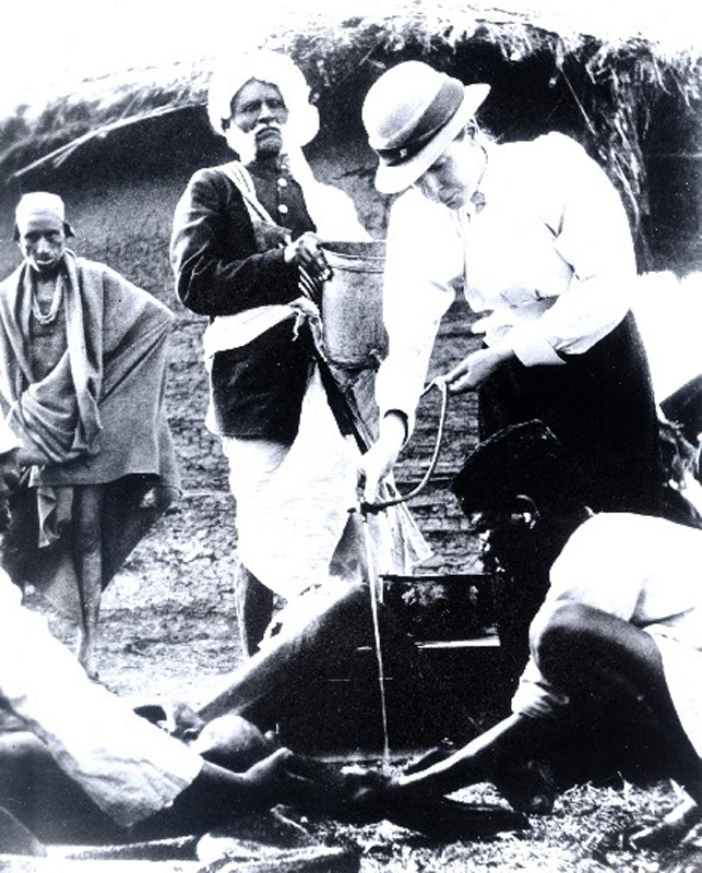 Rosalie Harvey demonstrating a practical way of washing ulcers using a bucket, hose and tap. Nasik, India. 1901