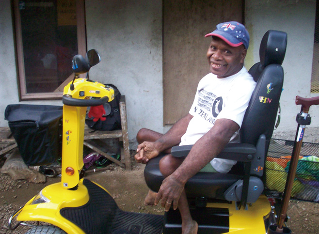 A smiling Issac sits atop his mobility scooter in Vanuatu.
